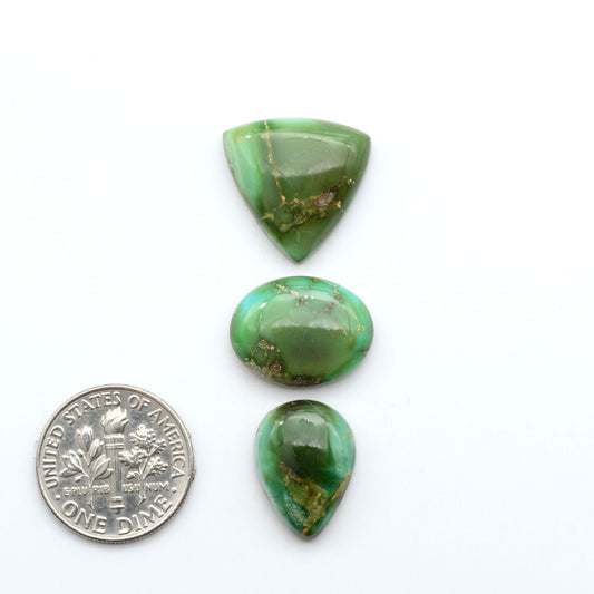 Sonoran Mountain Turquoise cabochons, blue-green color with natural matrix, polished stones on a white background, with a US dime for scale