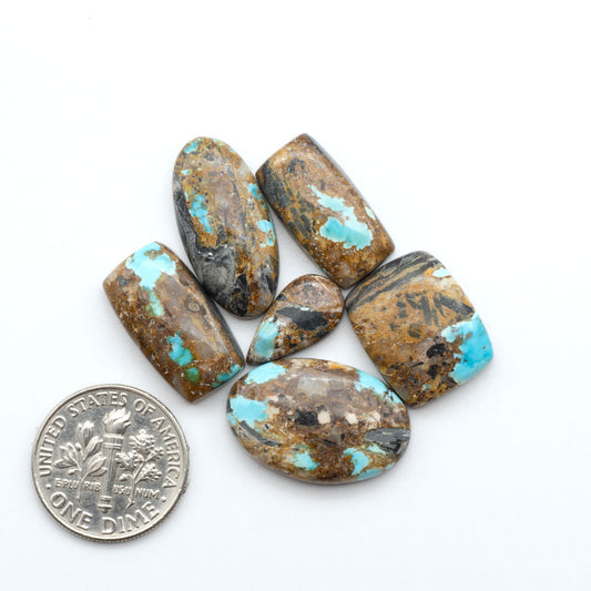 Black Jack turquoise cabochons, blue-green color with black matrix, polished stones on a white background with a US dime for scale