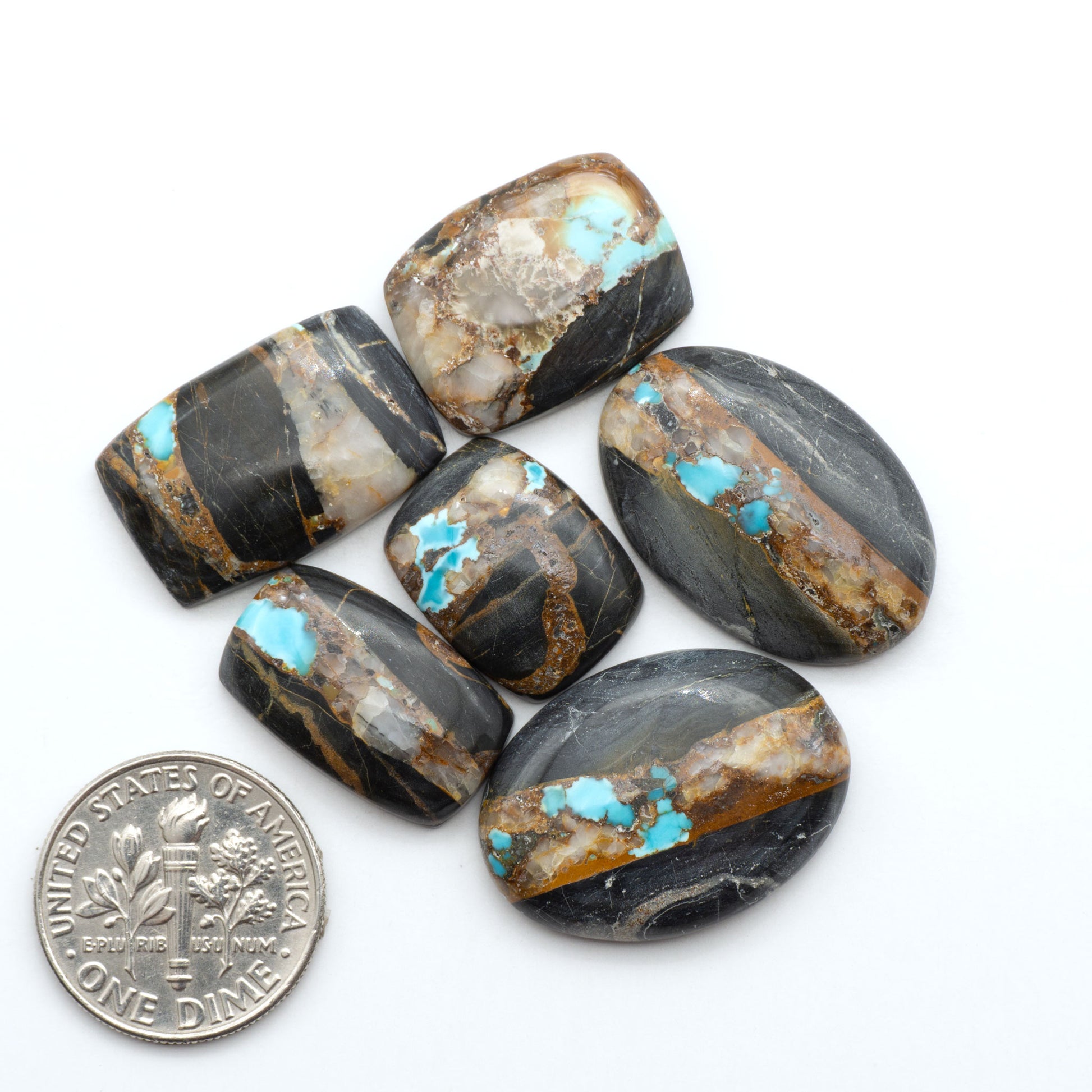 Black Jack turquoise cabochons, blue-green color with black matrix, polished stones on a white background with a US dime for scale