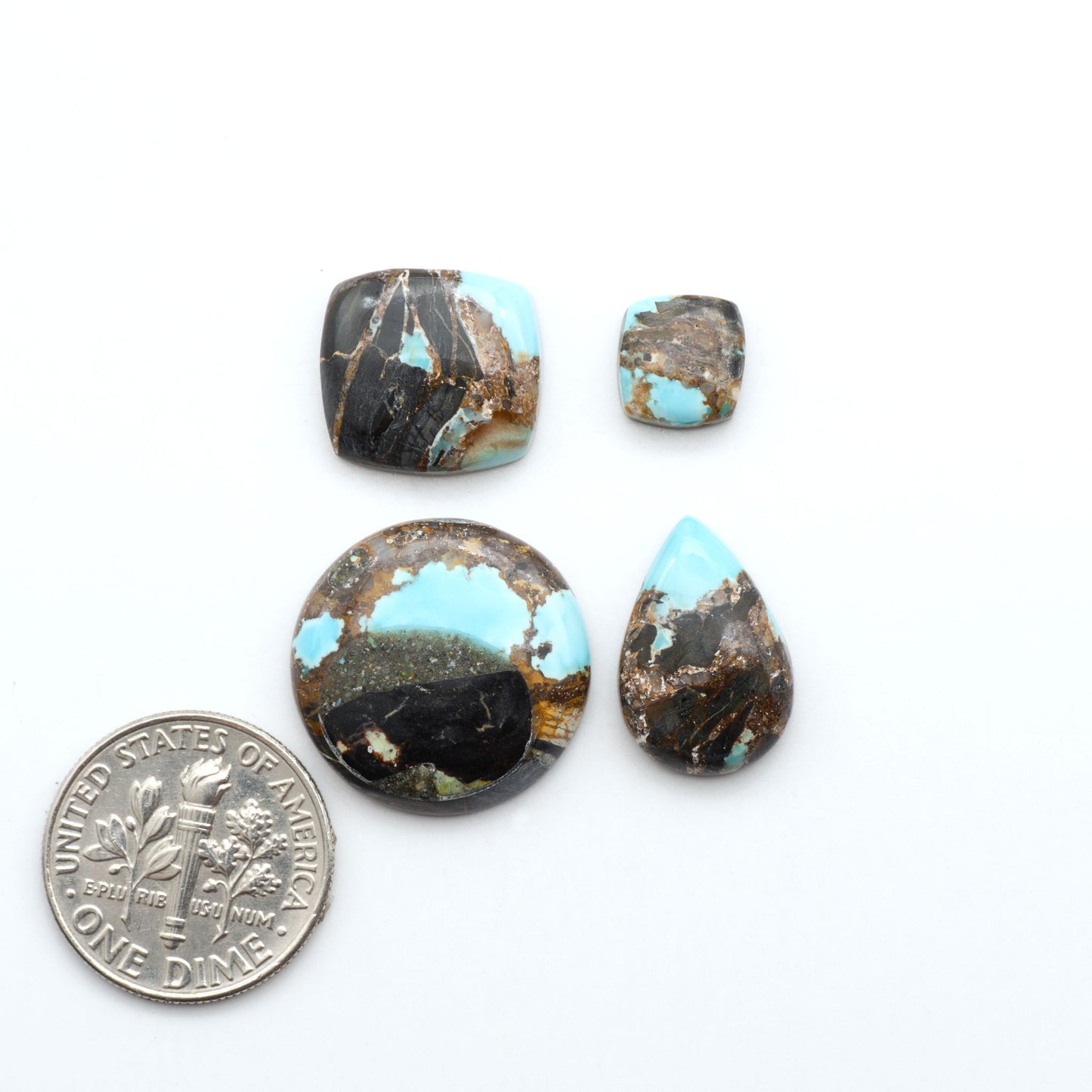 Black Jack turquoise cabochons, blue-green color with black matrix, polished stones on a white background with a US dime for scale