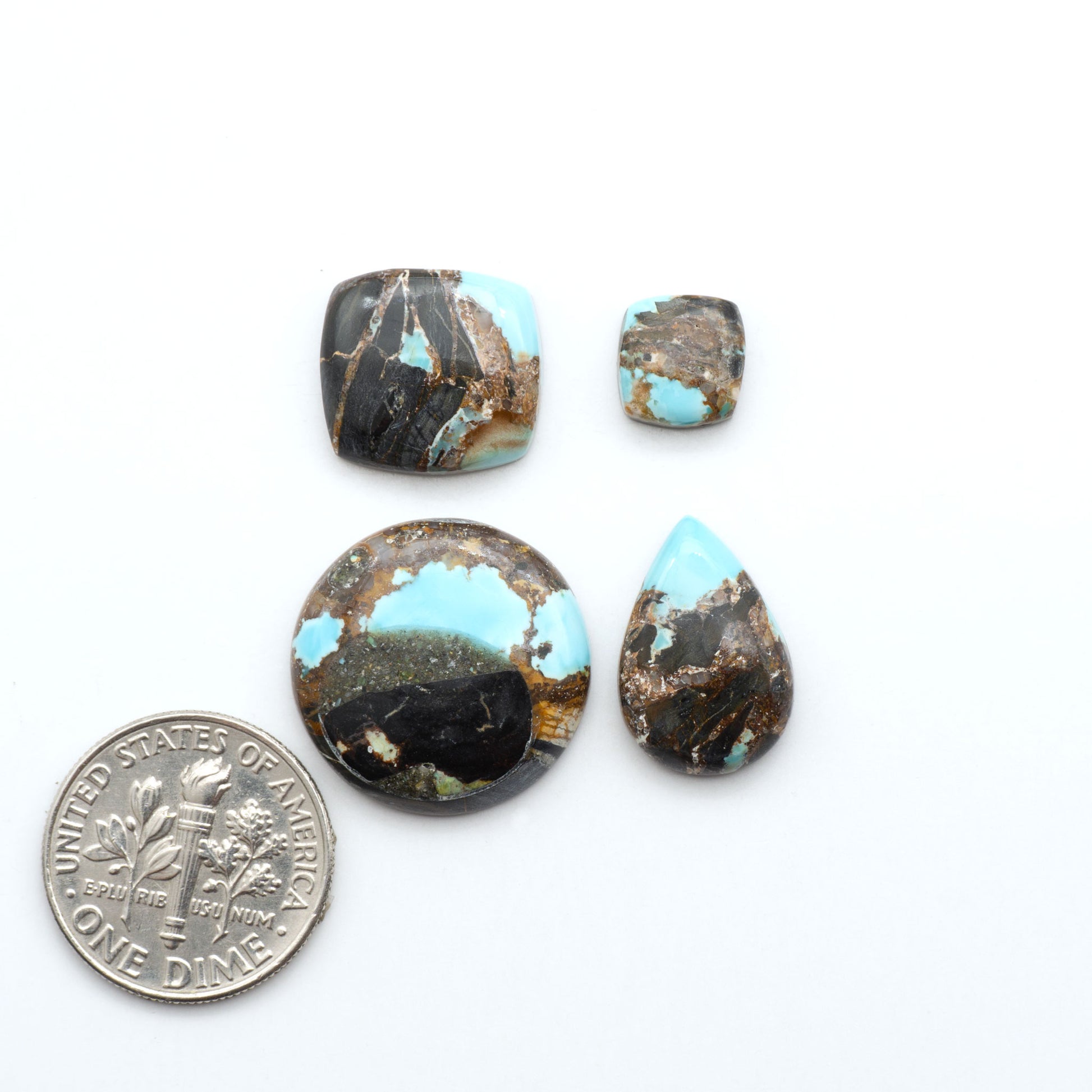 Black Jack turquoise cabochons, blue-green color with black matrix, polished stones on a white background with a US dime for scale