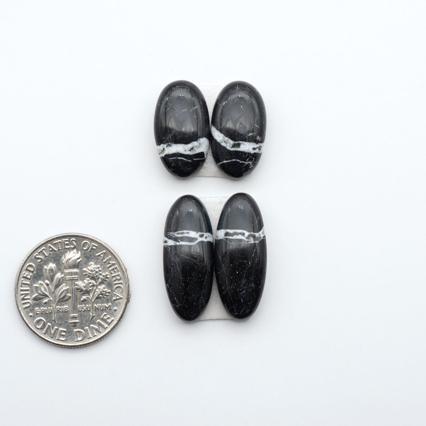 White Buffalo stone cabochons, white stone with black matrix, polished stones on a white background, with a US dime for scale