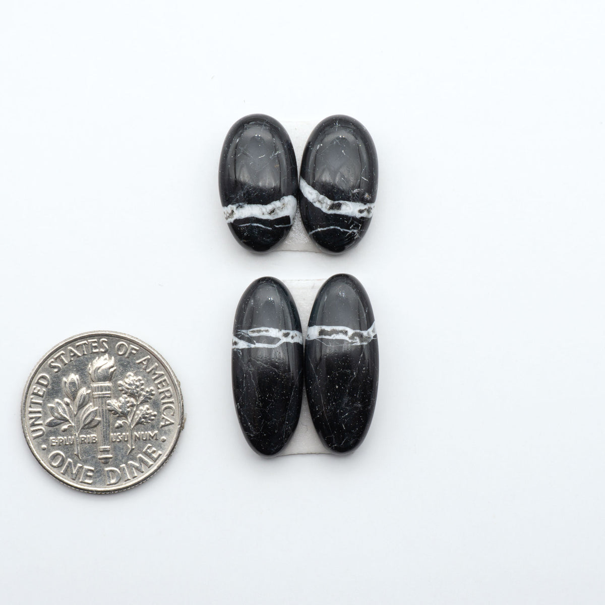 White Buffalo stone cabochons, white stone with black matrix, polished stones on a white background, with a US dime for scale