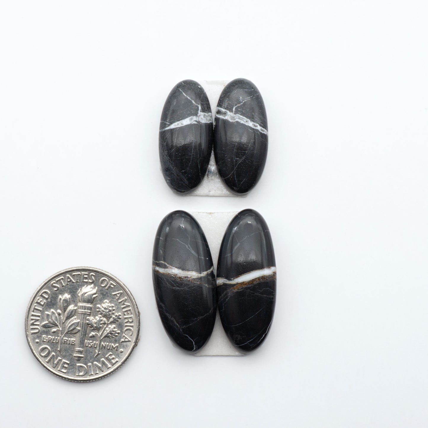 White Buffalo stone cabochons, white stone with black matrix, polished stones on a white background, with a US dime for scale