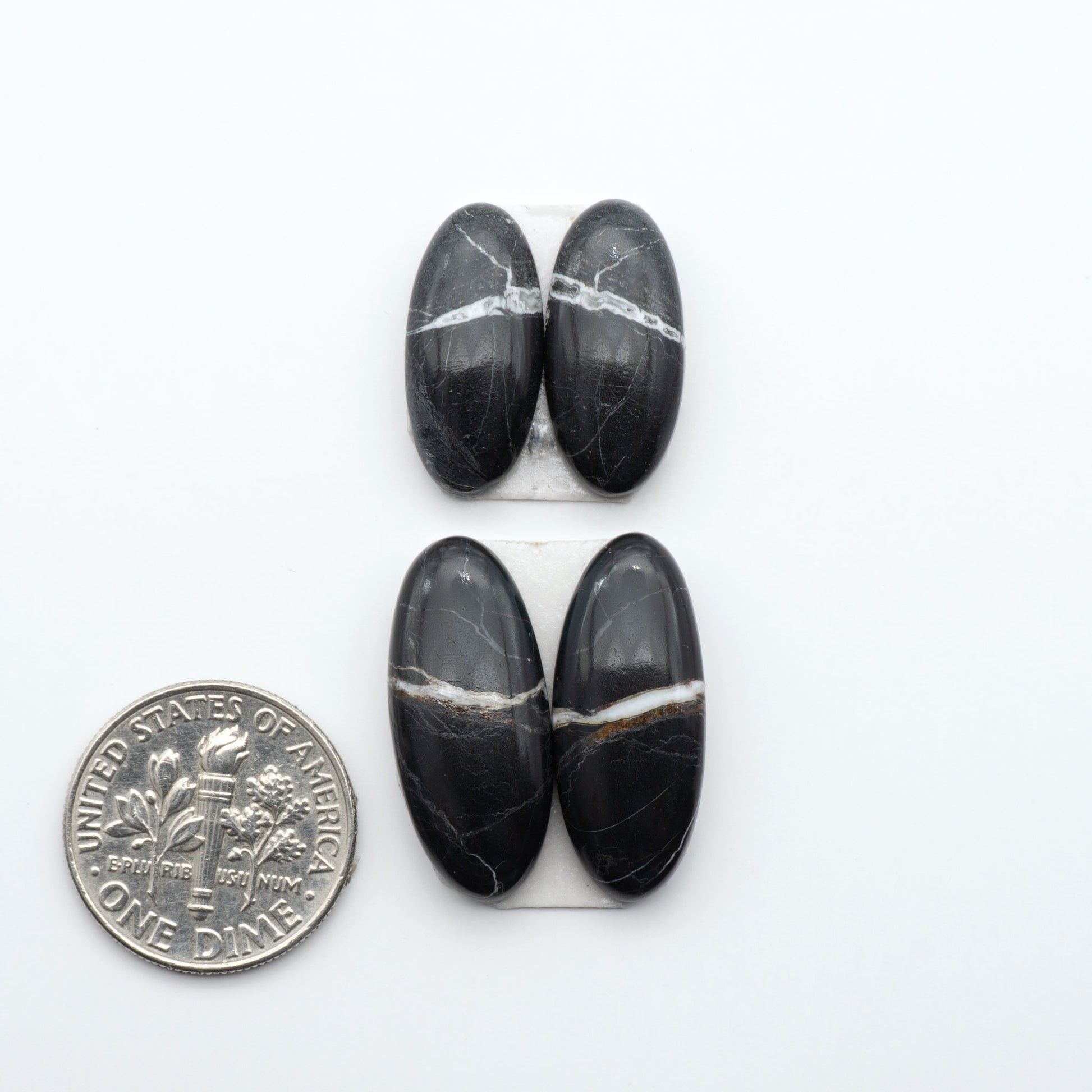 White Buffalo stone cabochons, white stone with black matrix, polished stones on a white background, with a US dime for scale