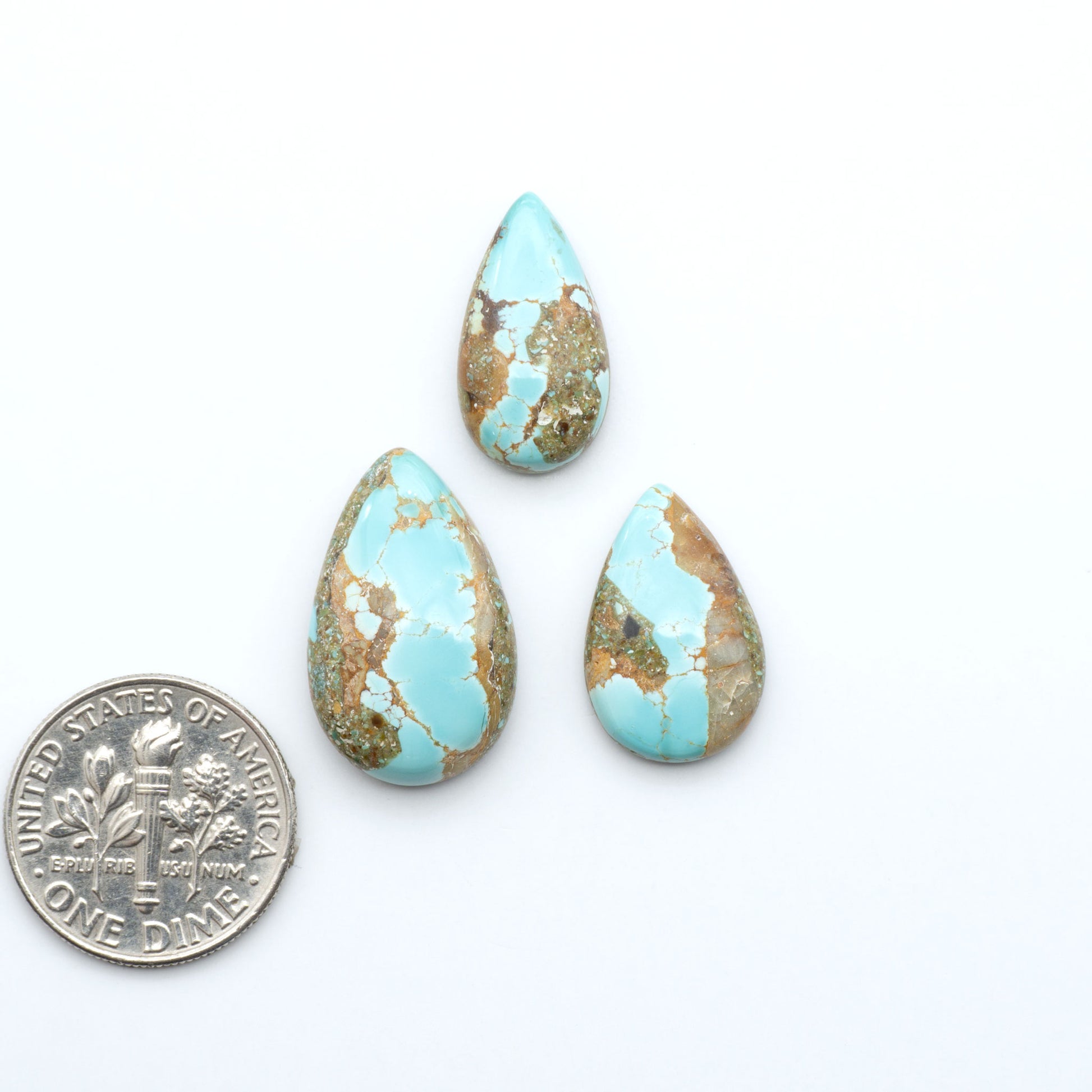 Royston Turquoise cabochons, blue-green color with natural matrix, polished stones on a white background, with a US dime for scale