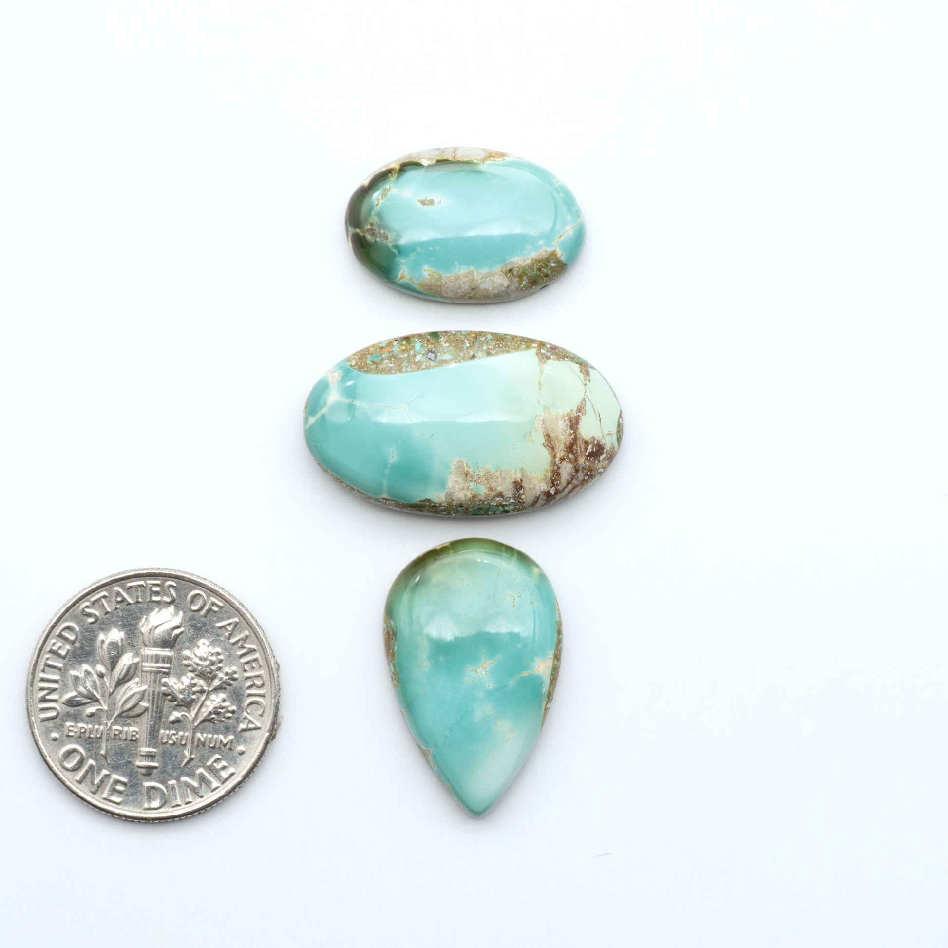 Royston Turquoise cabochons, blue-green color with natural matrix, polished stones on a white background, with a US dime for scale