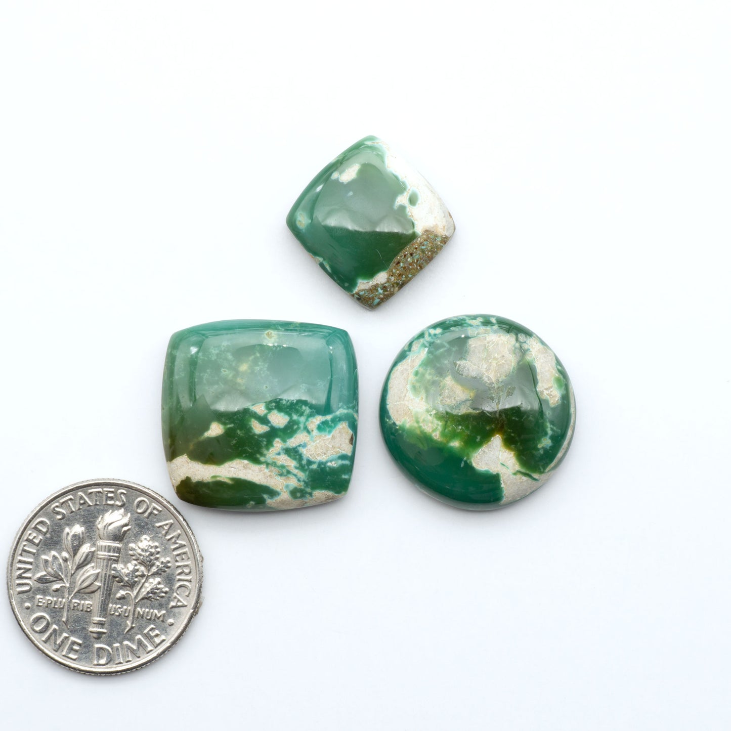 Royston Turquoise cabochons, blue-green color with natural matrix, polished stones on a white background, with a US dime for scale