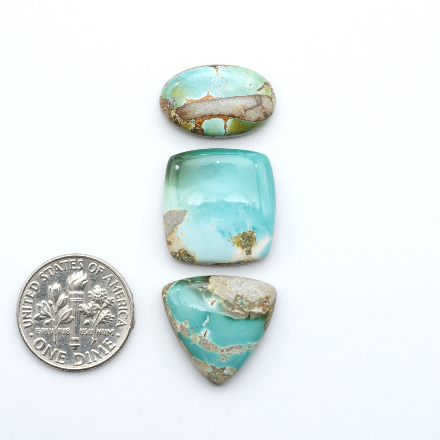 Royston Turquoise cabochons, blue-green color with natural matrix, polished stones on a white background, with a US dime for scale