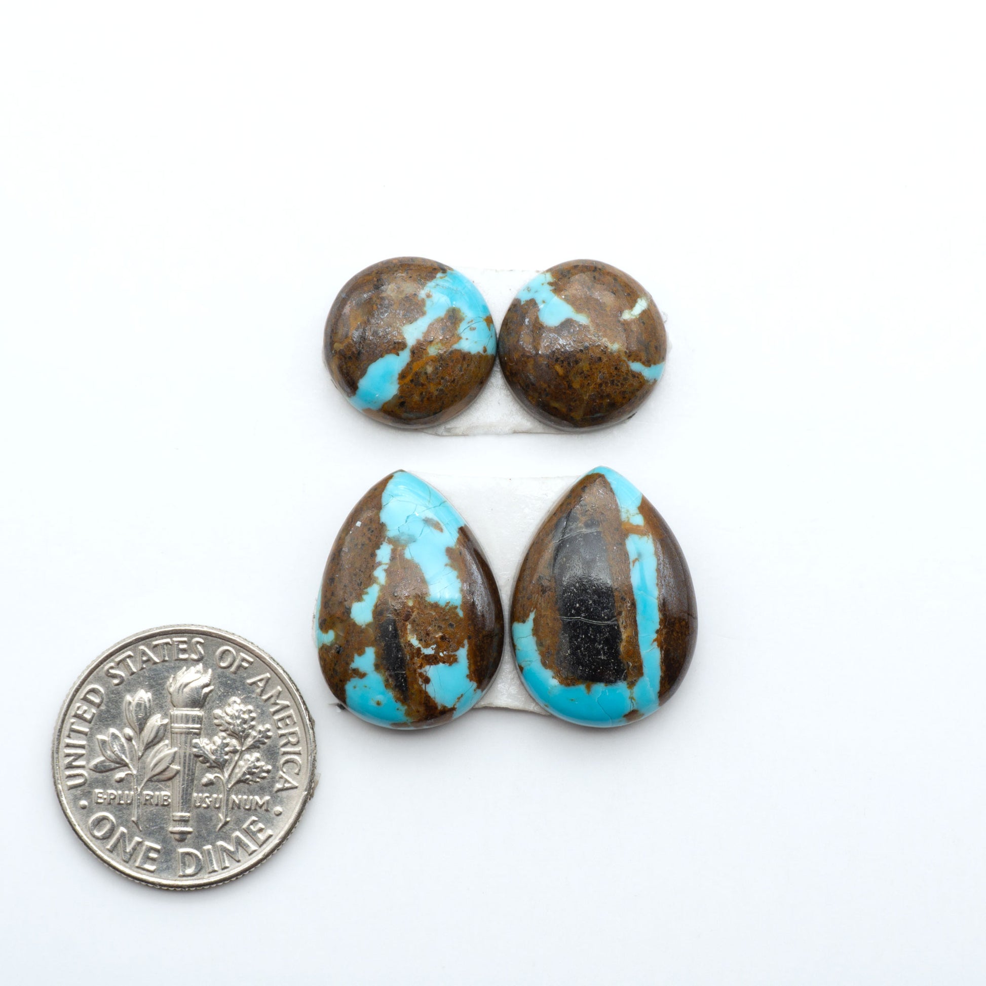 Number 8 Turquoise cabochons, blue and green color with brown matrix, polished stones on a white background, with a US dime for scale