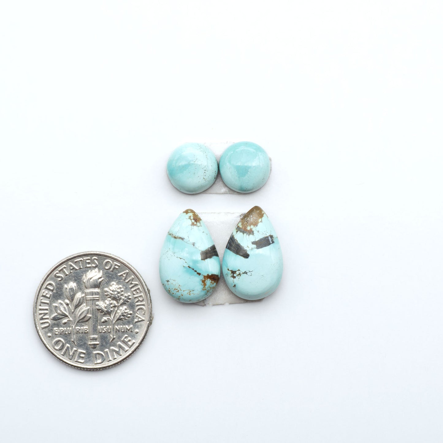 Number 8 Turquoise cabochons, blue and green color with brown matrix, polished stones on a white background, with a US dime for scale