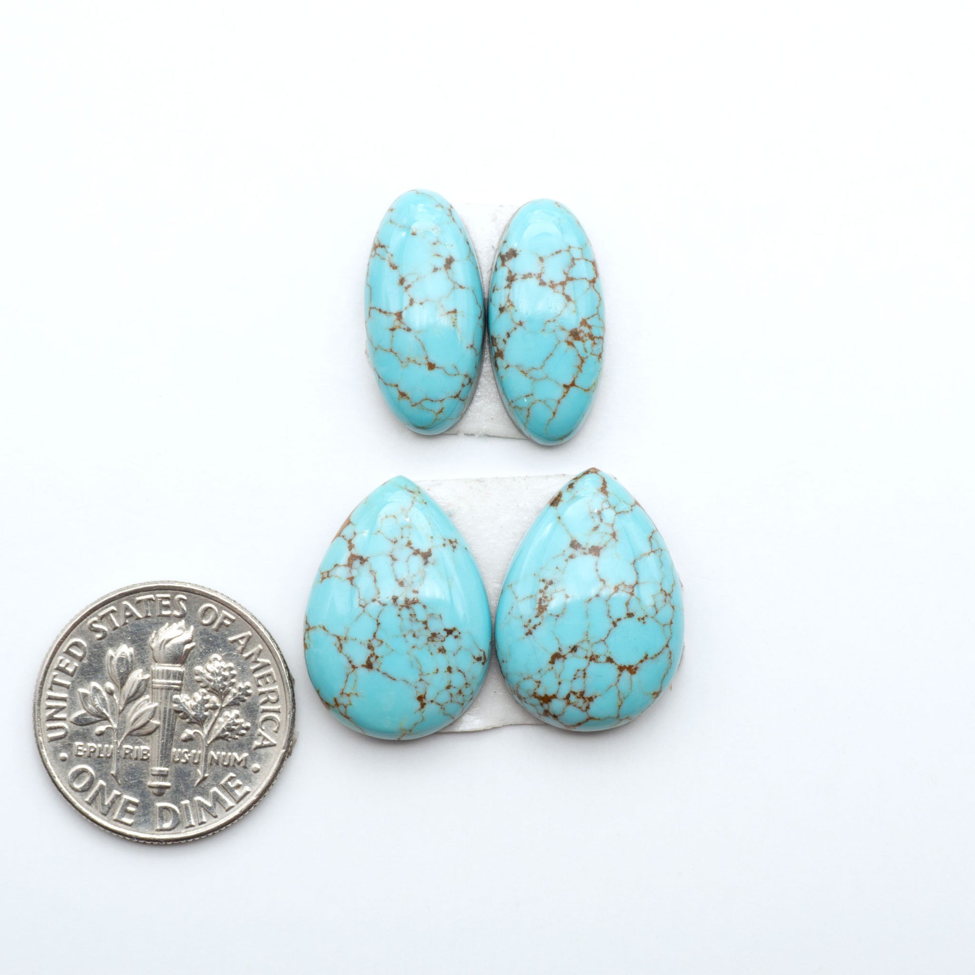 Number 8 Turquoise cabochons, blue and green color with brown matrix, polished stones on a white background, with a US dime for scale