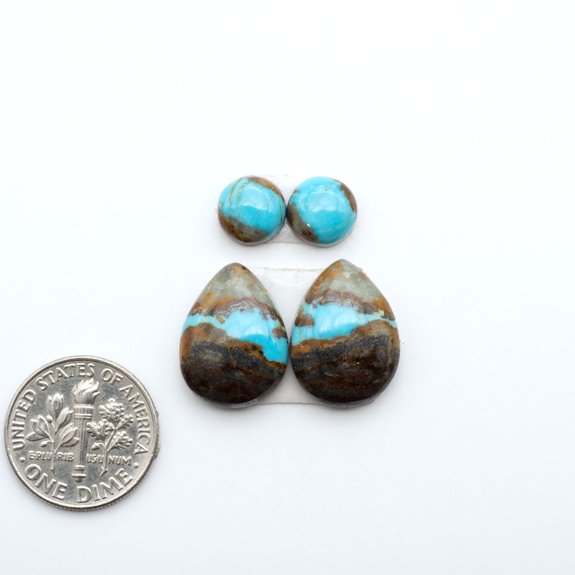 Number 8 Turquoise cabochons, blue and green color with brown matrix, polished stones on a white background, with a US dime for scale