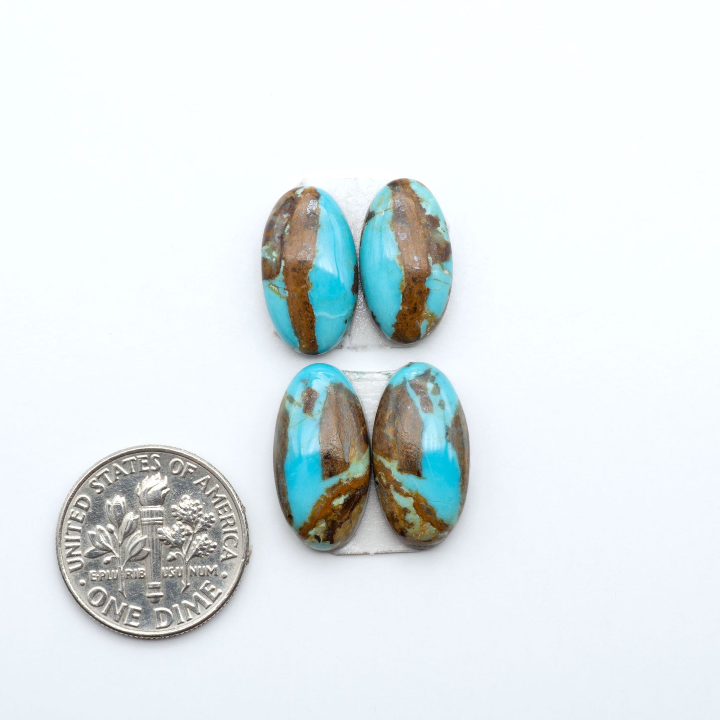 Number 8 Turquoise cabochons, blue and green color with brown matrix, polished stones on a white background, with a US dime for scale