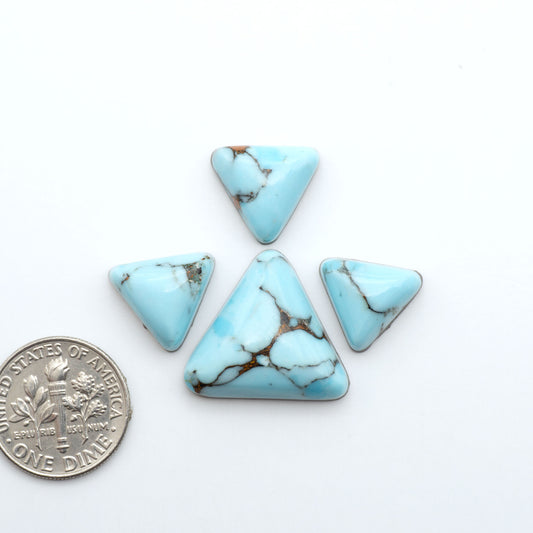 Pressed Turquoise nugget cabochons, composite material with a blue color and dark matrix on a white background, with a US dime for scale.