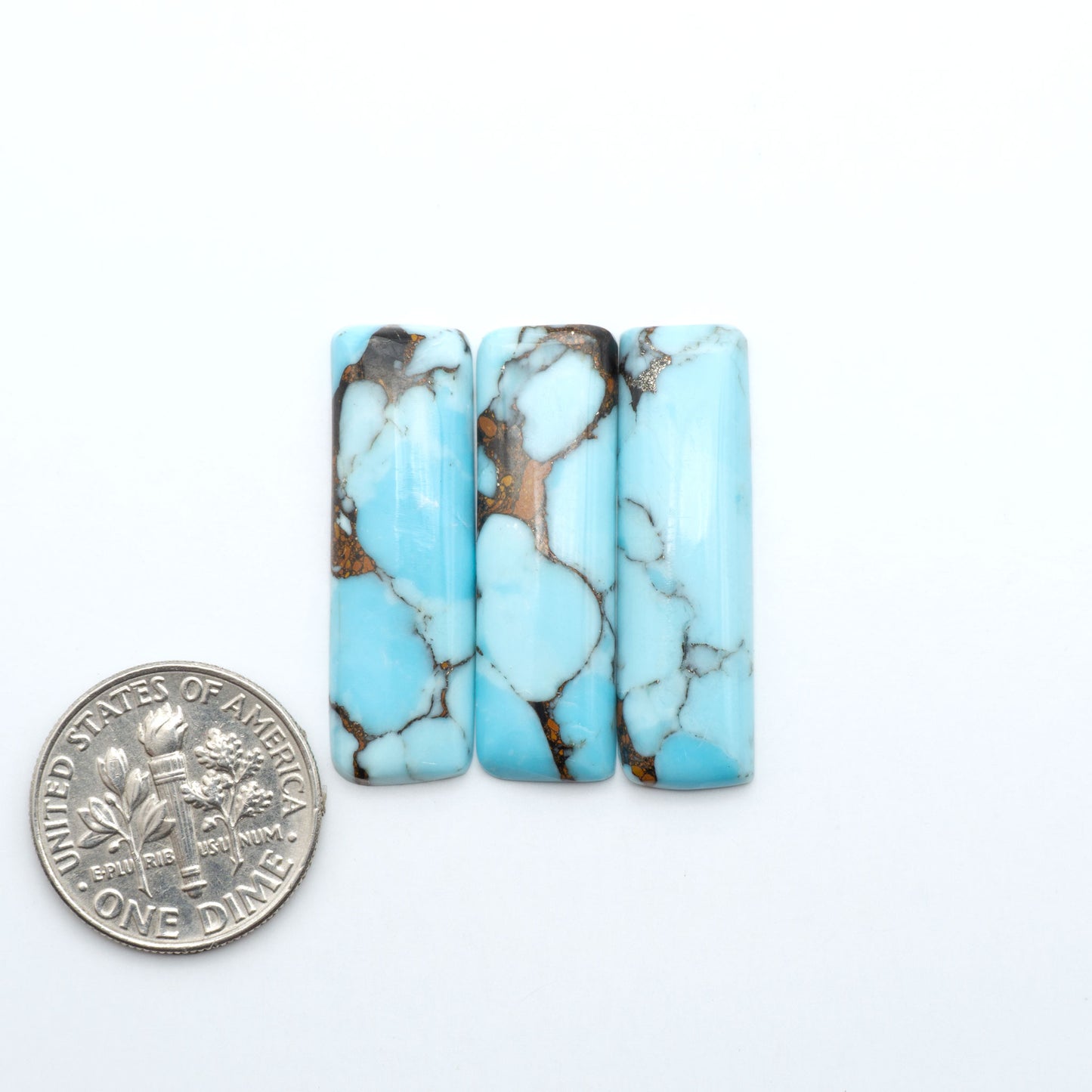 Pressed Turquoise nugget cabochons, composite material with a blue color and dark matrix on a white background, with a US dime for scale.