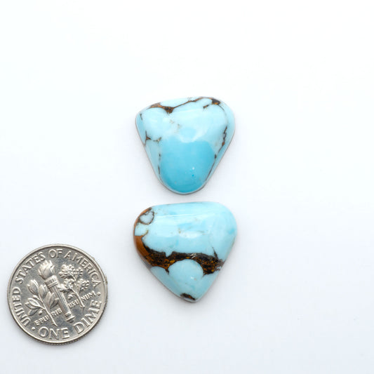 Pressed Turquoise nugget cabochons, composite material with a blue color and dark matrix on a white background, with a US dime for scale.
