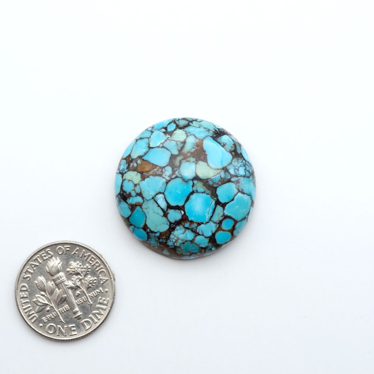 Pressed Turquoise nugget cabochons, composite material with a blue color and dark matrix on a white background, with a US dime for scale.