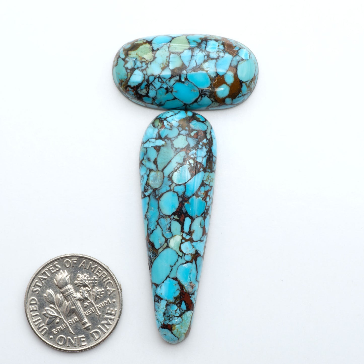 Pressed Turquoise nugget cabochons, composite material with a blue color and dark matrix on a white background, with a US dime for scale.