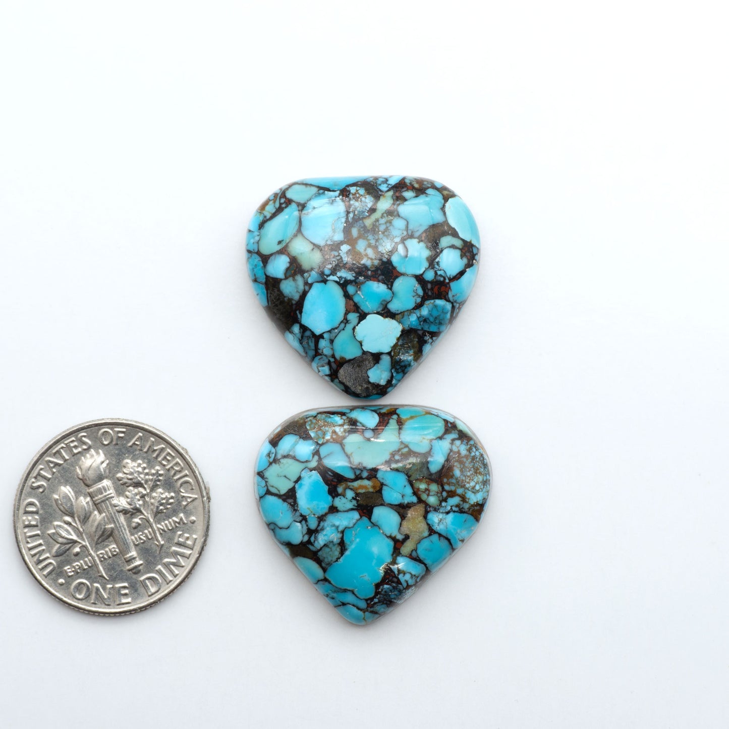 Pressed Turquoise nugget cabochons, composite material with a blue color and dark matrix on a white background, with a US dime for scale.