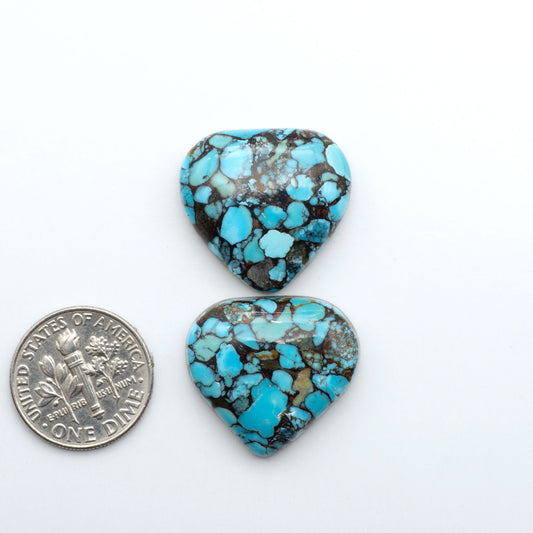 Pressed Turquoise nugget cabochons, composite material with a blue color and dark matrix on a white background, with a US dime for scale.