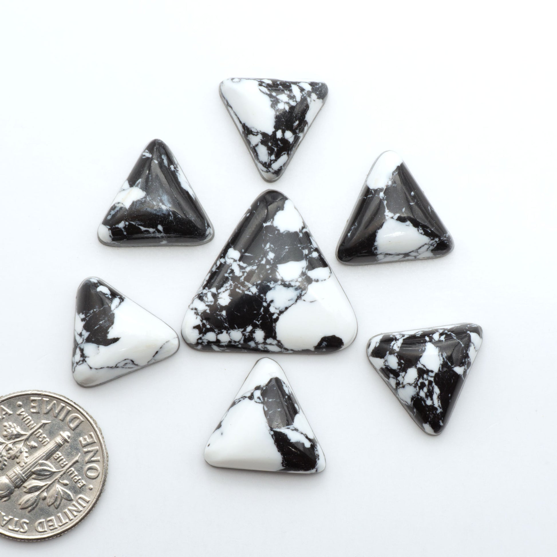 White Buffalo composite cabochons, black and white gemstones on a white background with a US dime for scale