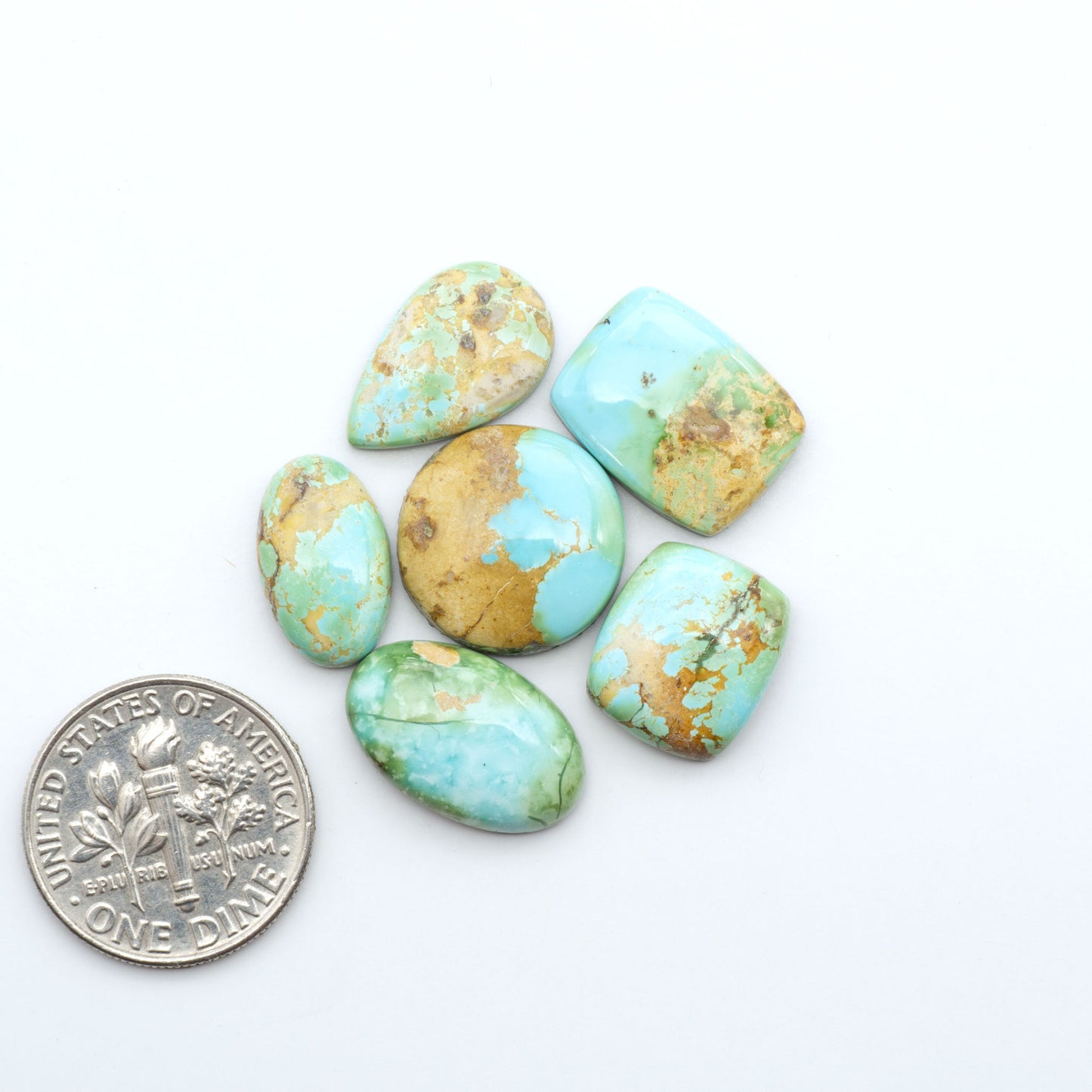 Sonoran Mountain Turquoise cabochons, blue-green color with natural matrix, polished stones on a white background, with a US dime for scale