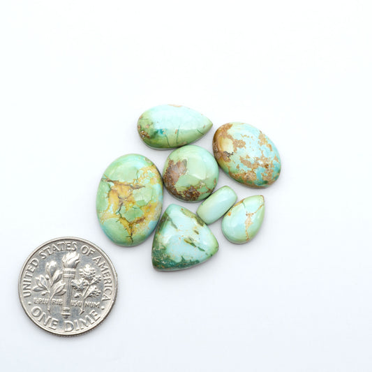 Sonoran Mountain Turquoise cabochons, blue-green color with natural matrix, polished stones on a white background, with a US dime for scale
