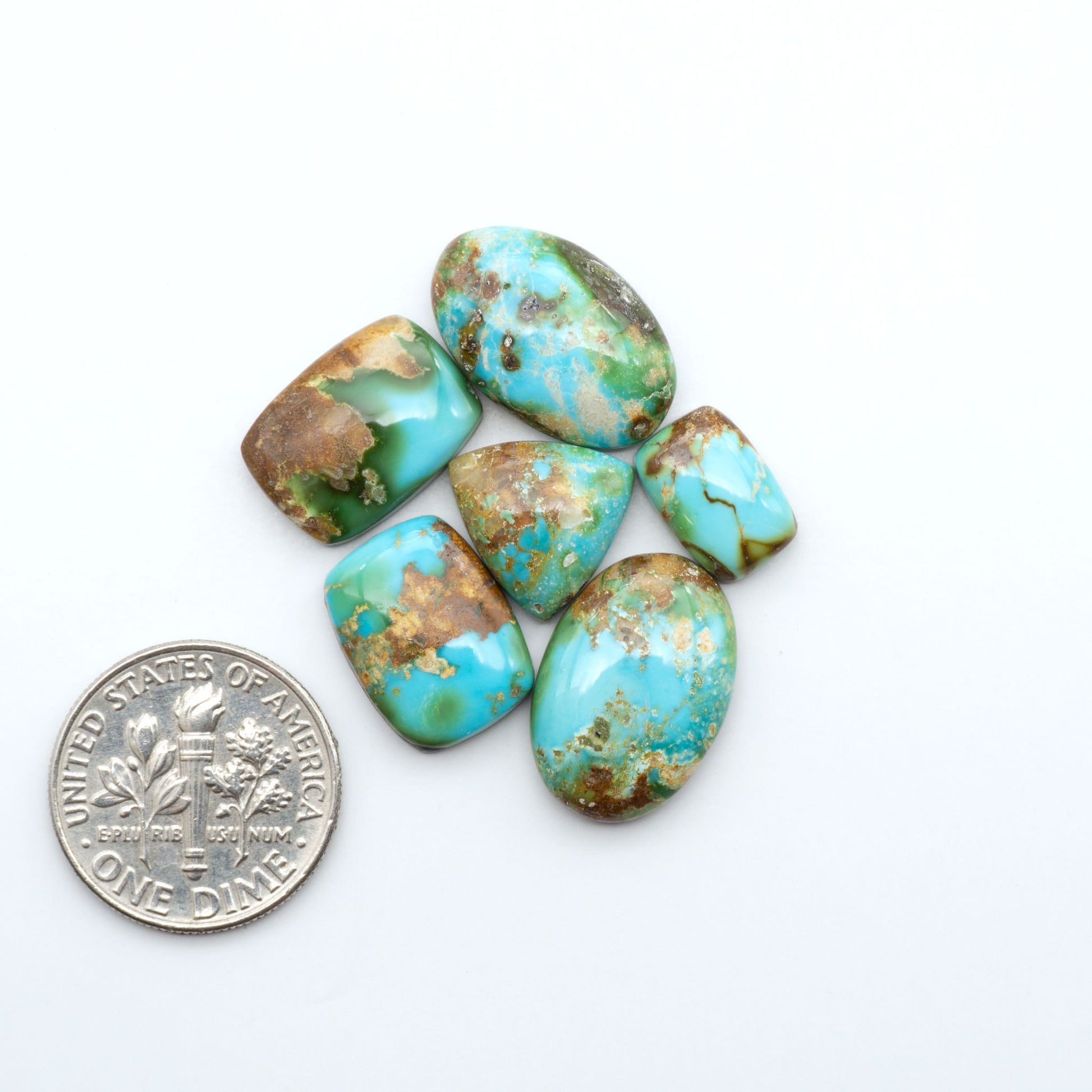 Sonoran Mountain Turquoise cabochons, blue-green color with natural matrix, polished stones on a white background, with a US dime for scale