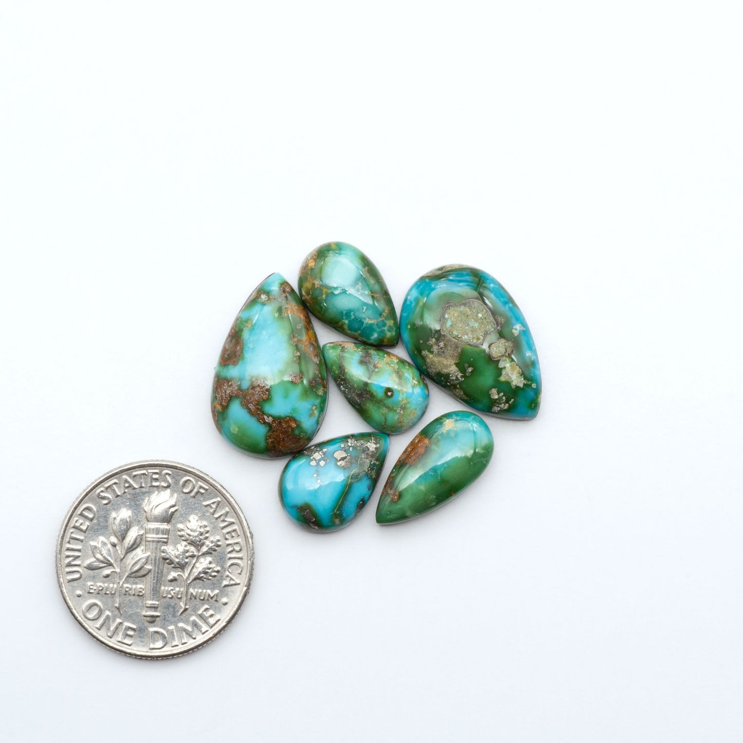 Sonoran Mountain Turquoise cabochons, blue-green color with natural matrix, polished stones on a white background, with a US dime for scale