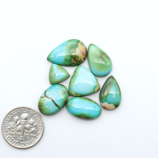 Sonoran Mountain Turquoise cabochons, blue-green color with natural matrix, polished stones on a white background, with a US dime for scale