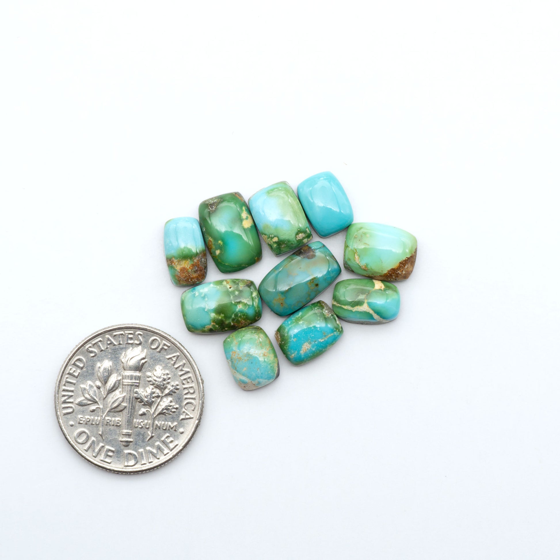 Sonoran Mountain Turquoise cabochons, blue-green color with natural matrix, polished stones on a white background, with a US dime for scale