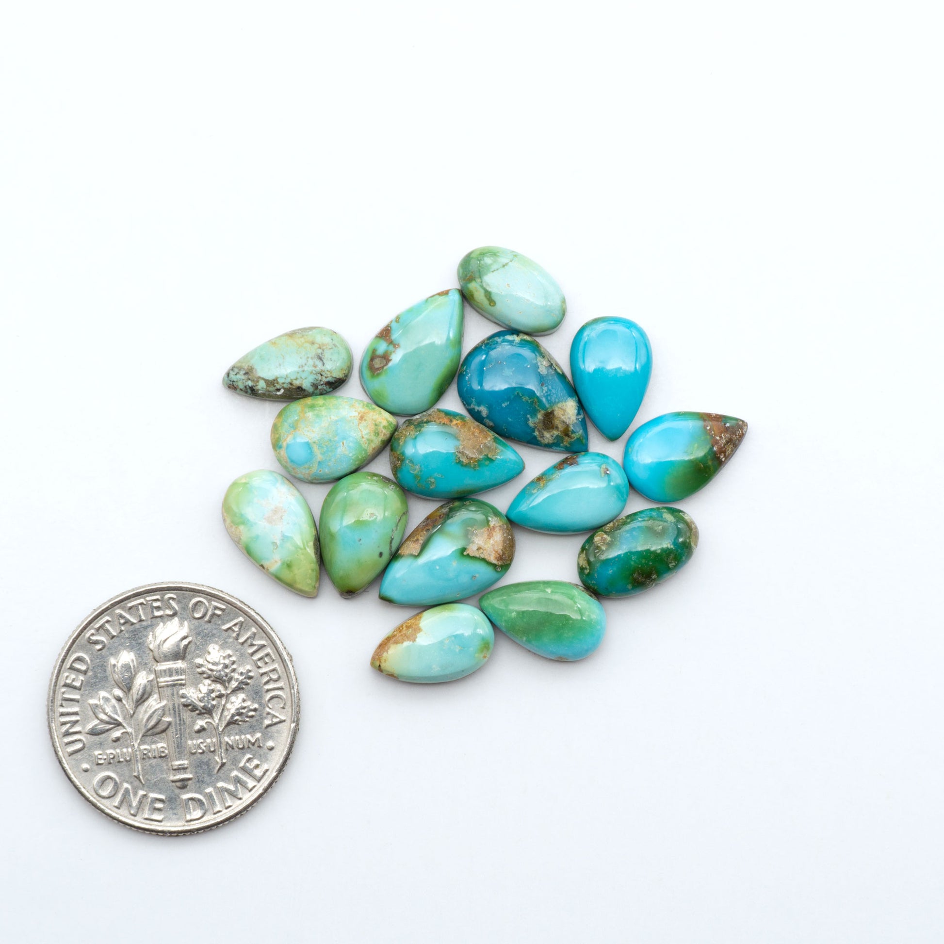 Sonoran Mountain Turquoise cabochons, blue-green color with natural matrix, polished stones on a white background, with a US dime for scale