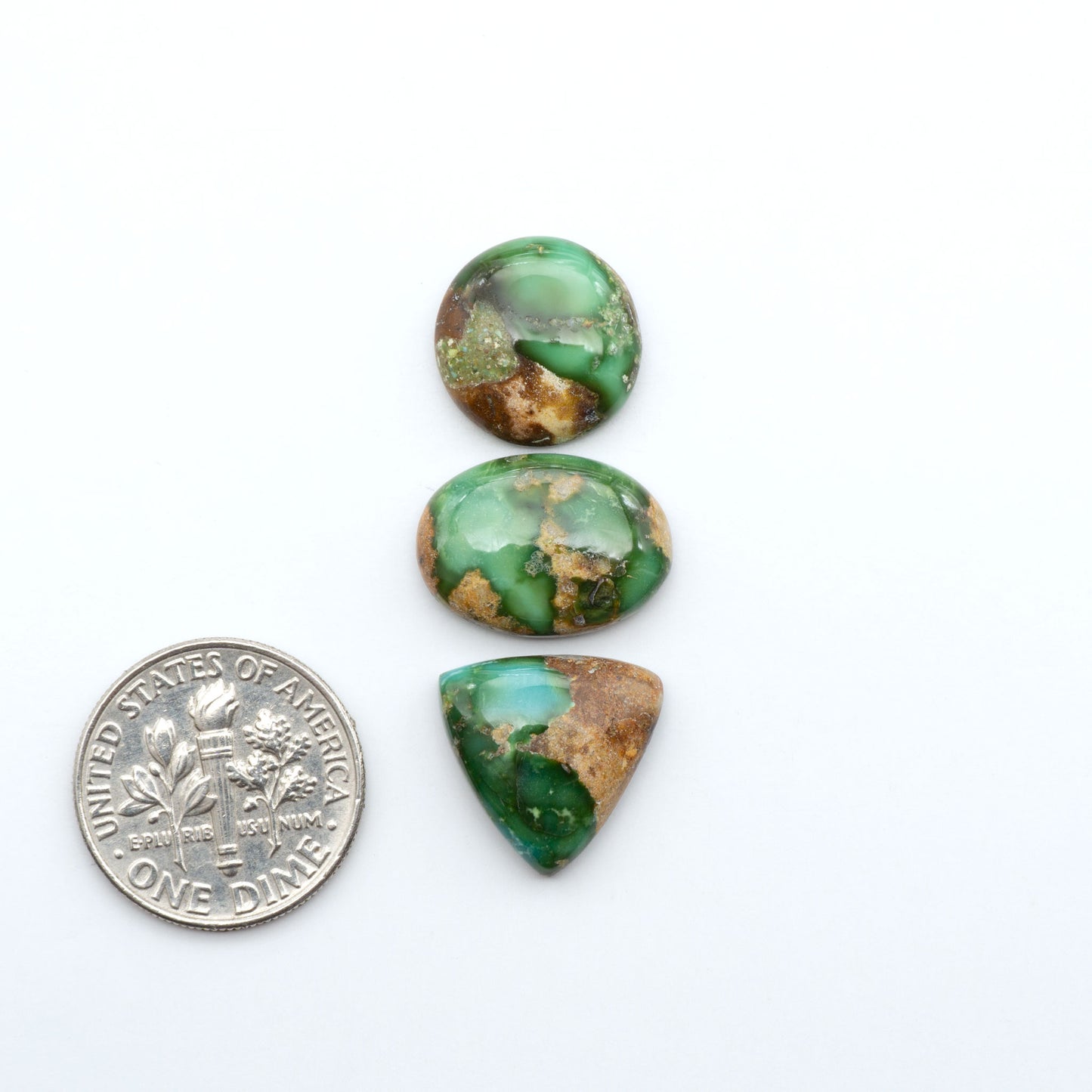 Sonoran Mountain Turquoise cabochons, blue-green color with natural matrix, polished stones on a white background, with a US dime for scale