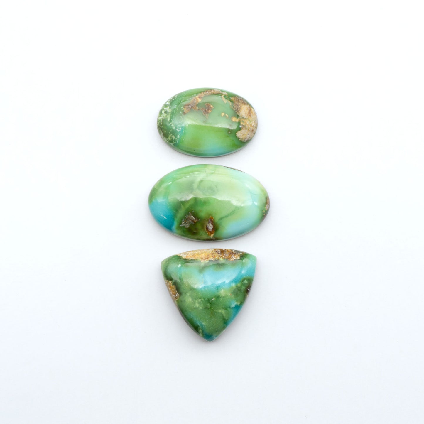 Sonoran Mountain Turquoise cabochons, blue-green color with natural matrix, polished stones on a white background, with a US dime for scale