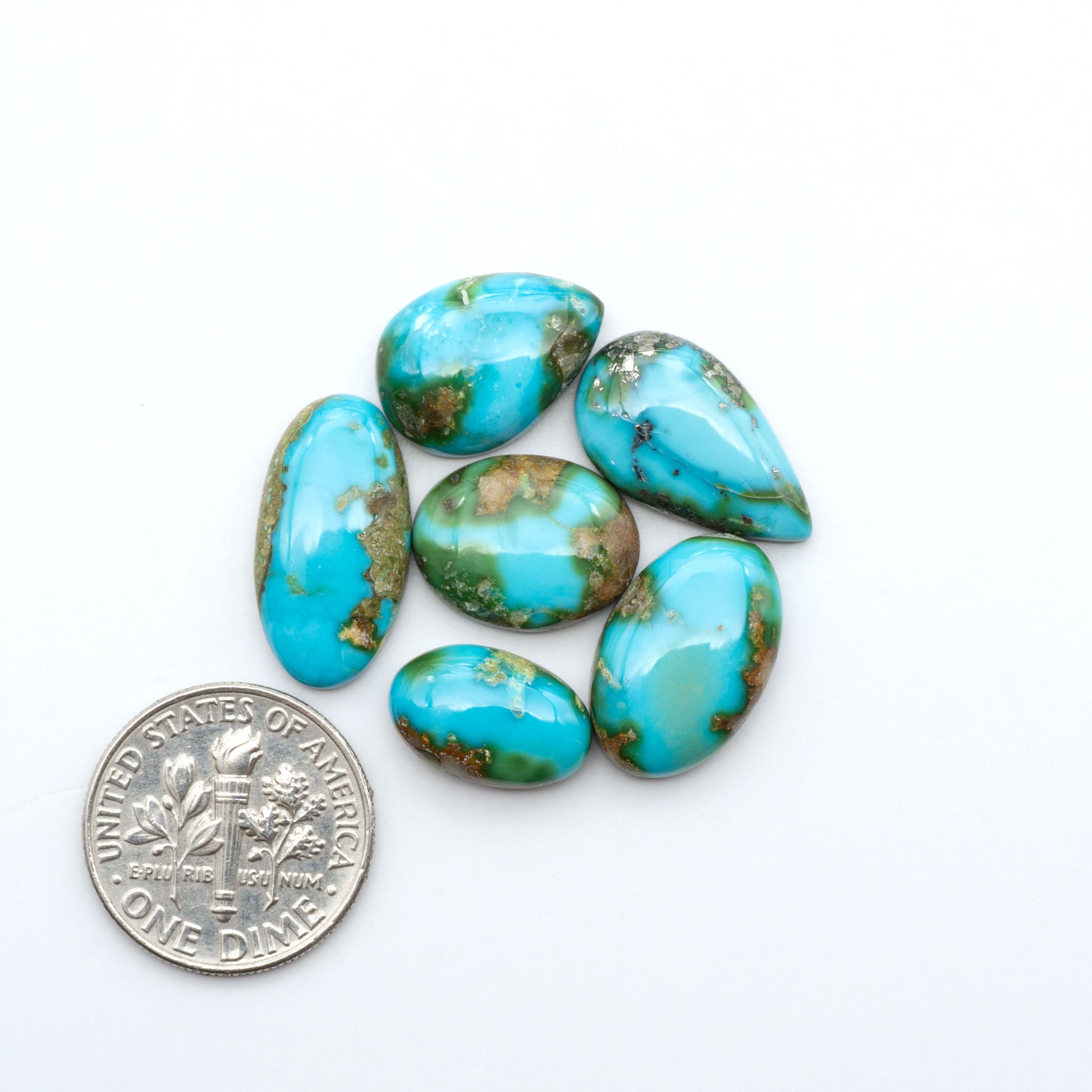Sonoran Mountain Turquoise cabochons, blue-green color with natural matrix, polished stones on a white background, with a US dime for scale