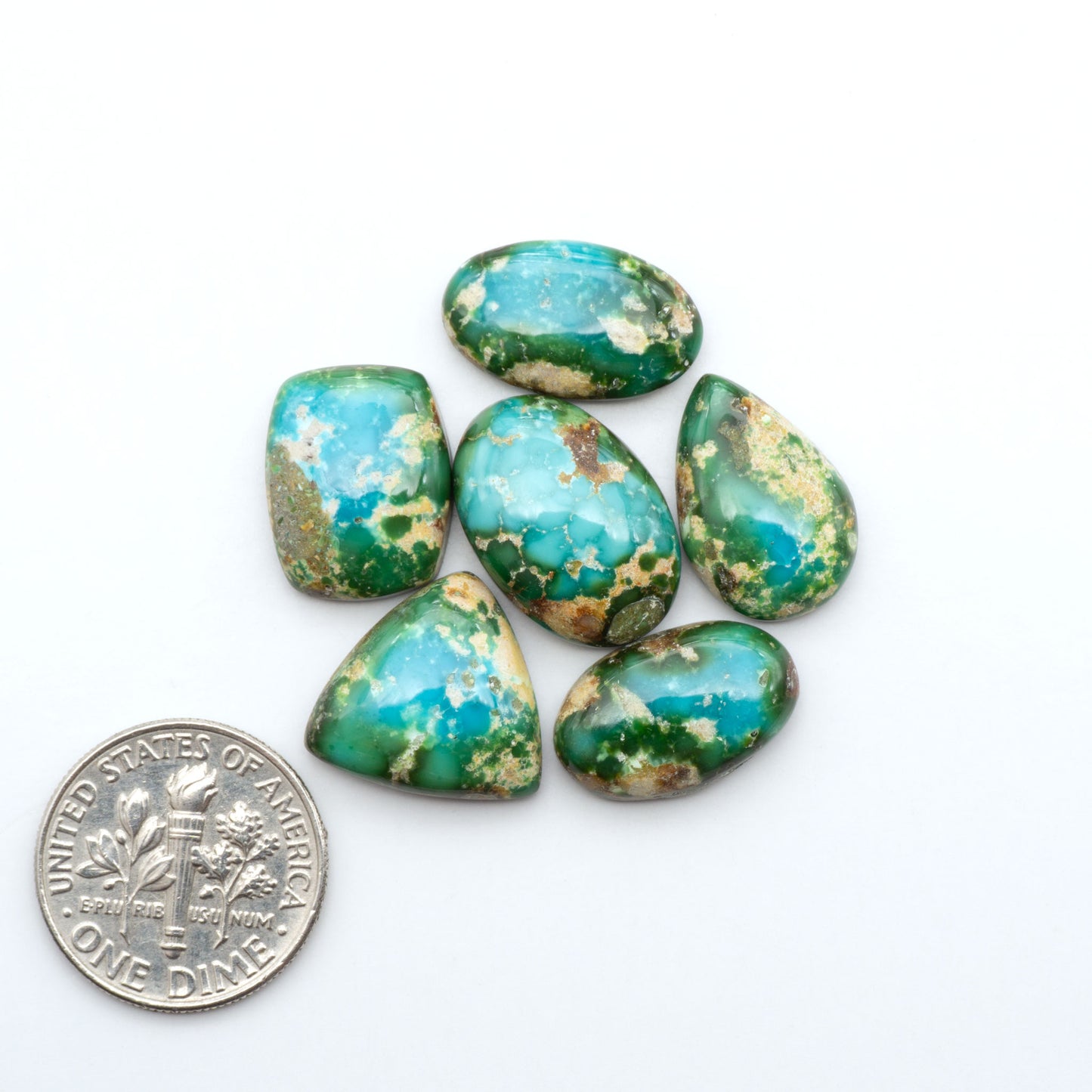 Sonoran Mountain Turquoise cabochons, blue-green color with natural matrix, polished stones on a white background, with a US dime for scale