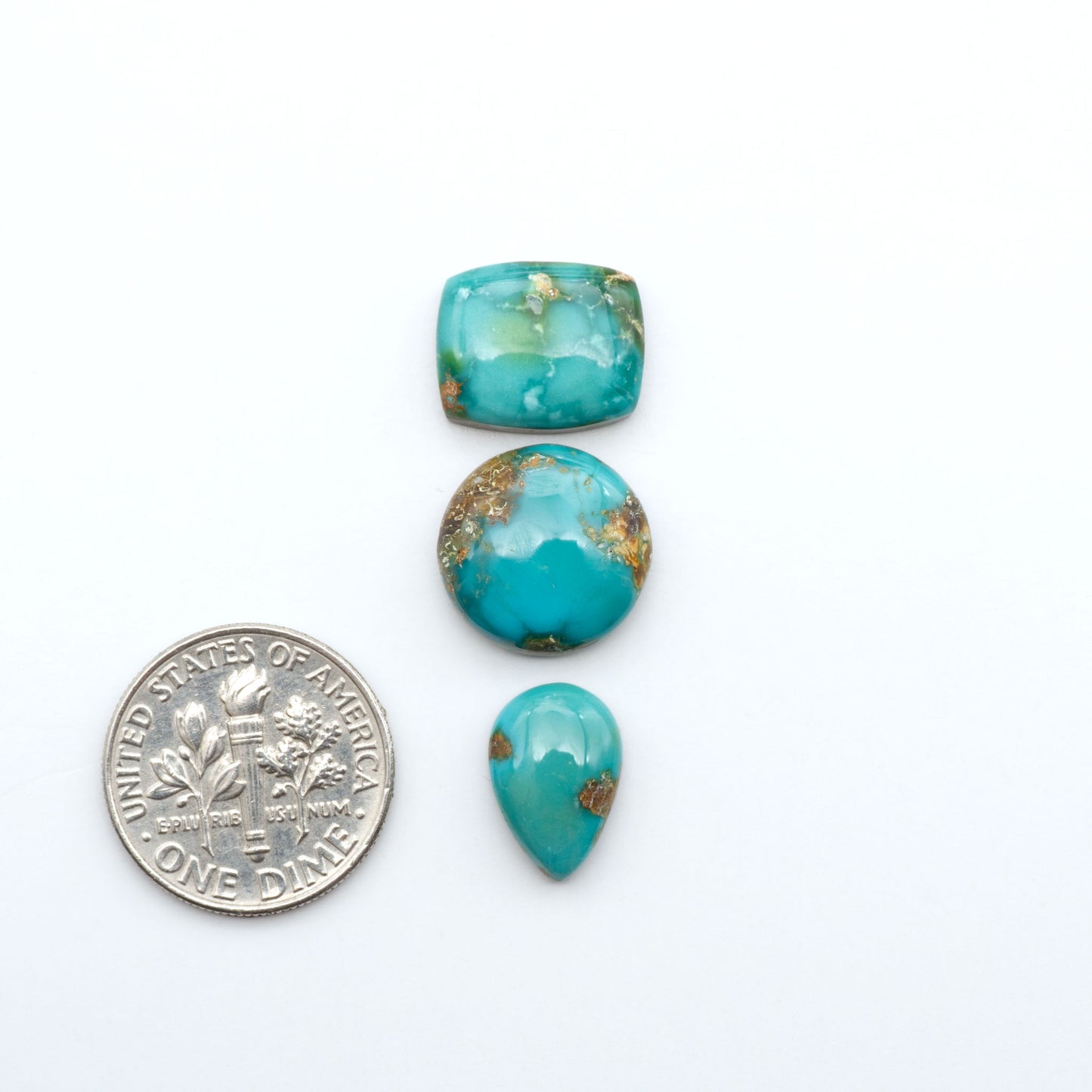 Sonoran Mountain Turquoise cabochons, blue-green color with natural matrix, polished stones on a white background, with a US dime for scale