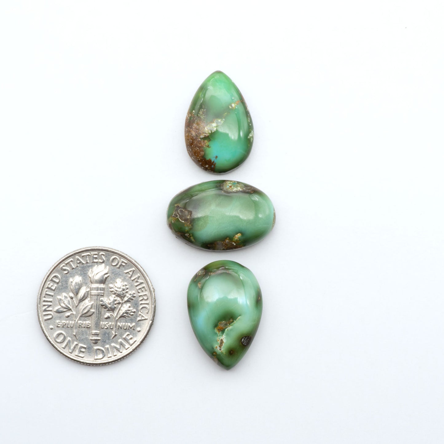 Sonoran Mountain Turquoise cabochons, blue-green color with natural matrix, polished stones on a white background, with a US dime for scale
