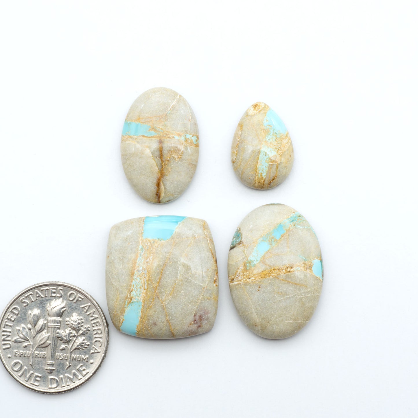 Royston Turquoise cabochons, blue-green color with natural matrix, polished stones on a white background, with a US dime for scale
