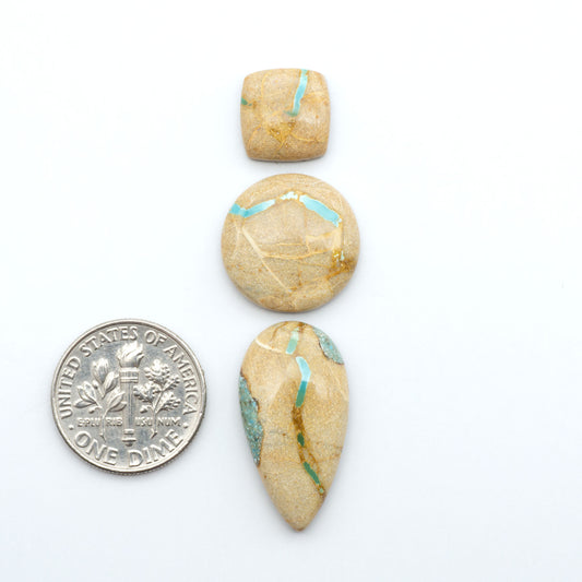 Royston Turquoise cabochons, blue-green color with natural matrix, polished stones on a white background, with a US dime for scale