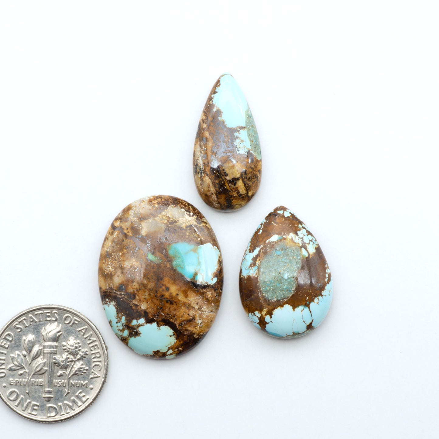 Royston Turquoise cabochons, blue-green color with natural matrix, polished stones on a white background, with a US dime for scale