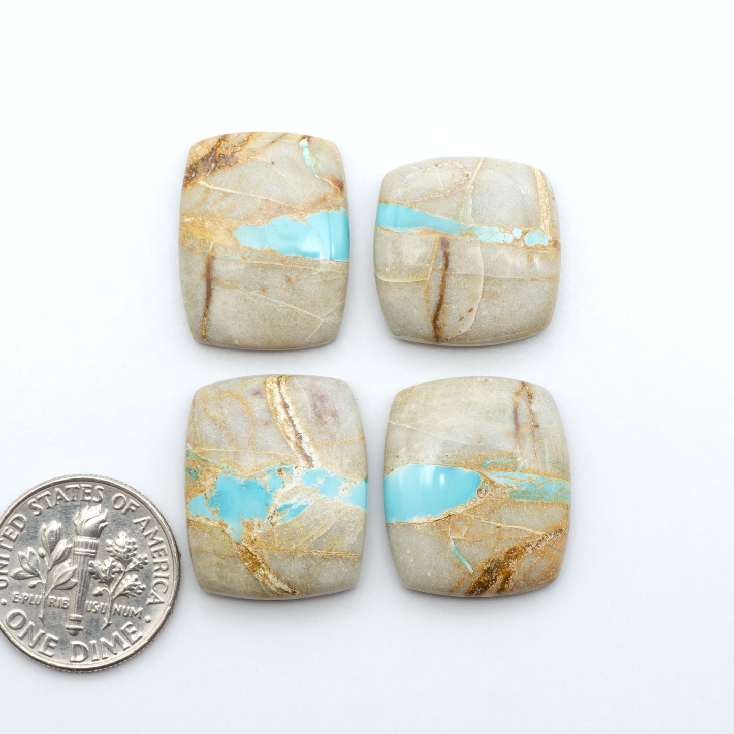 Royston Turquoise cabochons, blue-green color with natural matrix, polished stones on a white background, with a US dime for scale