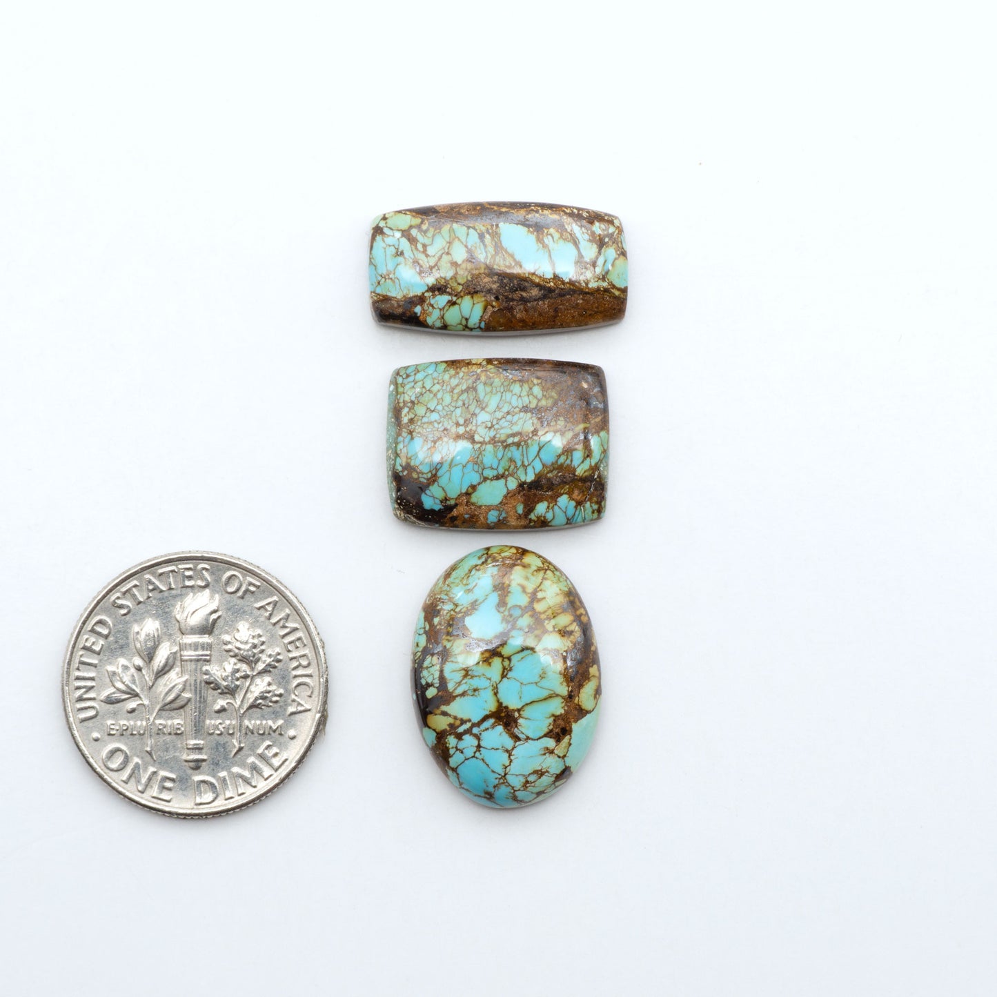 Royston Turquoise cabochons, blue-green color with natural matrix, polished stones on a white background, with a US dime for scale