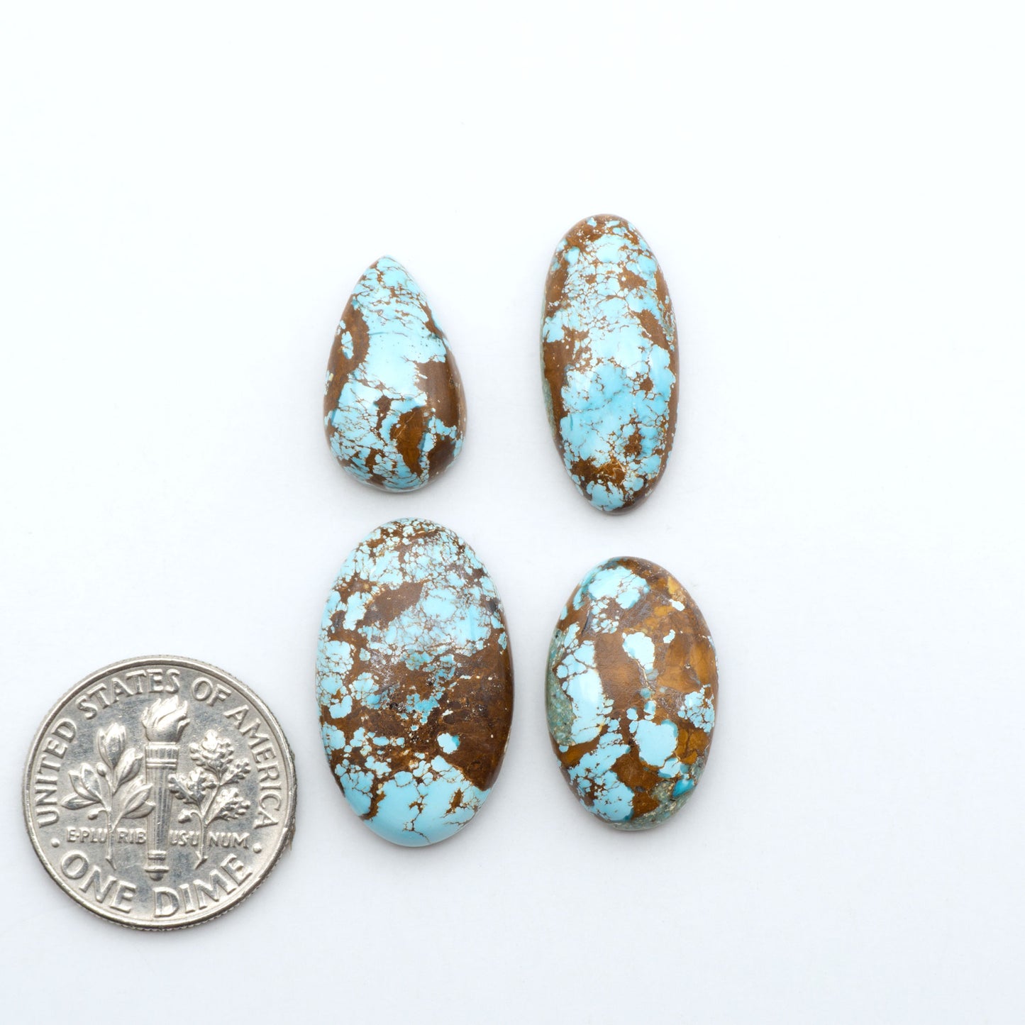 Royston Turquoise cabochons, blue-green color with natural matrix, polished stones on a white background, with a US dime for scale