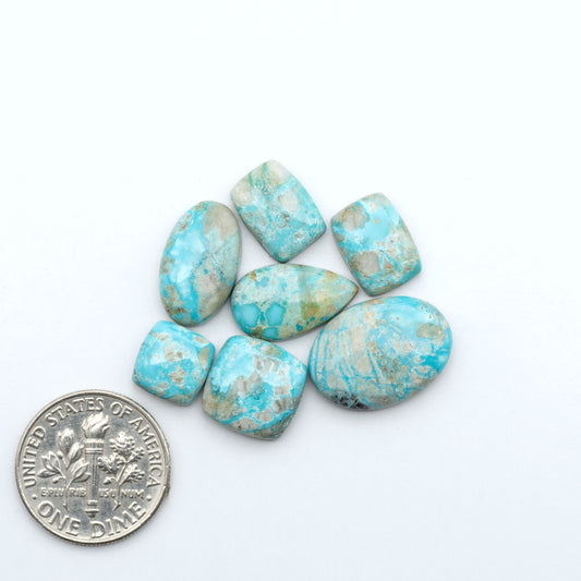Fox Turquoise cabochons, polished gemstones with natural matrix on a white background, with a US dime for scale
