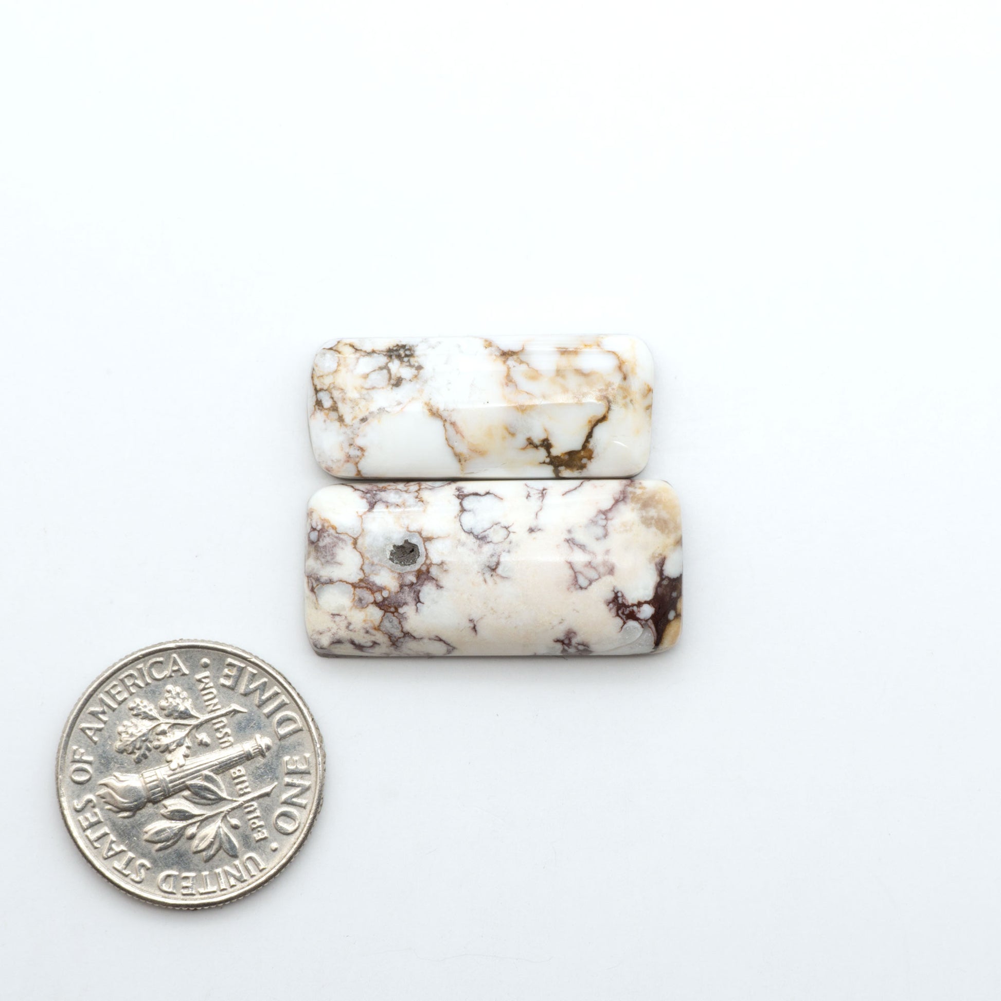 Wild Horse Magnesite cabochons, white gemstones with brown matrix on a white background, with a US dime for scale