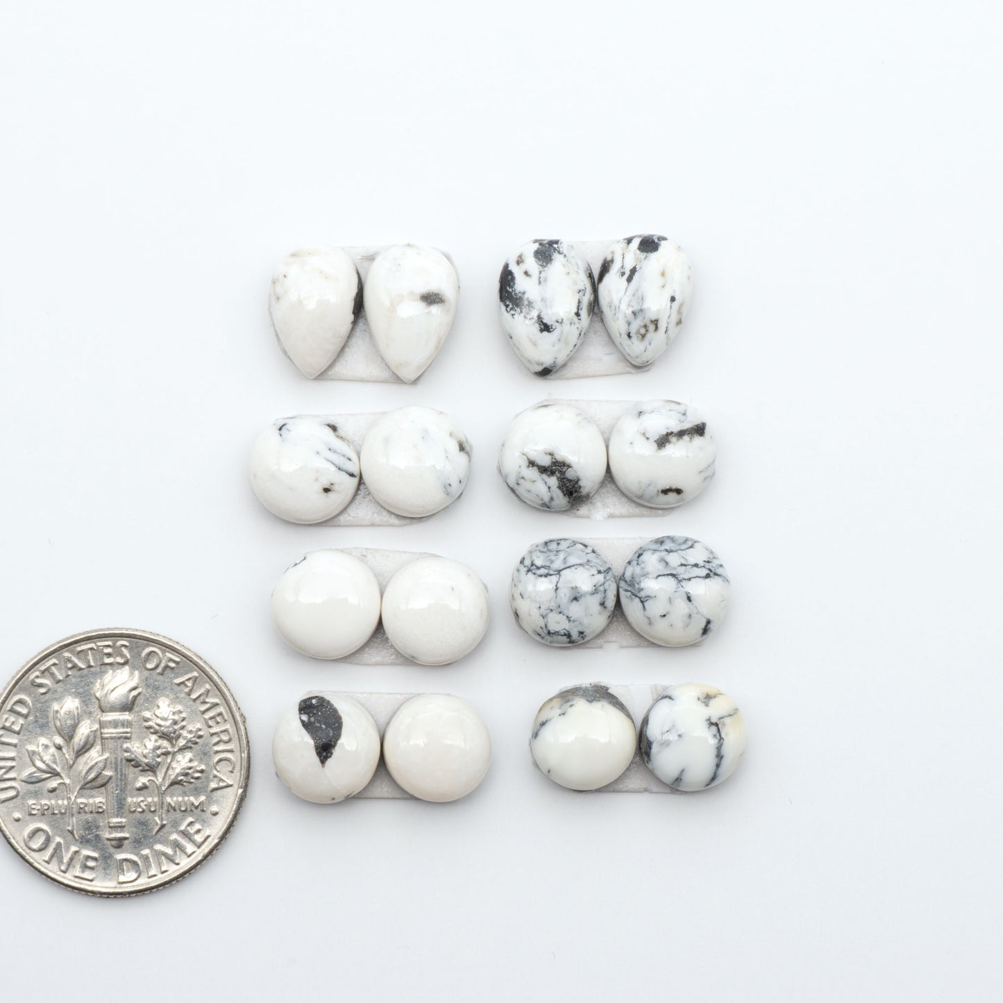 White Buffalo stone cabochons, white stone with black matrix, polished stones on a white background, with a US dime for scale