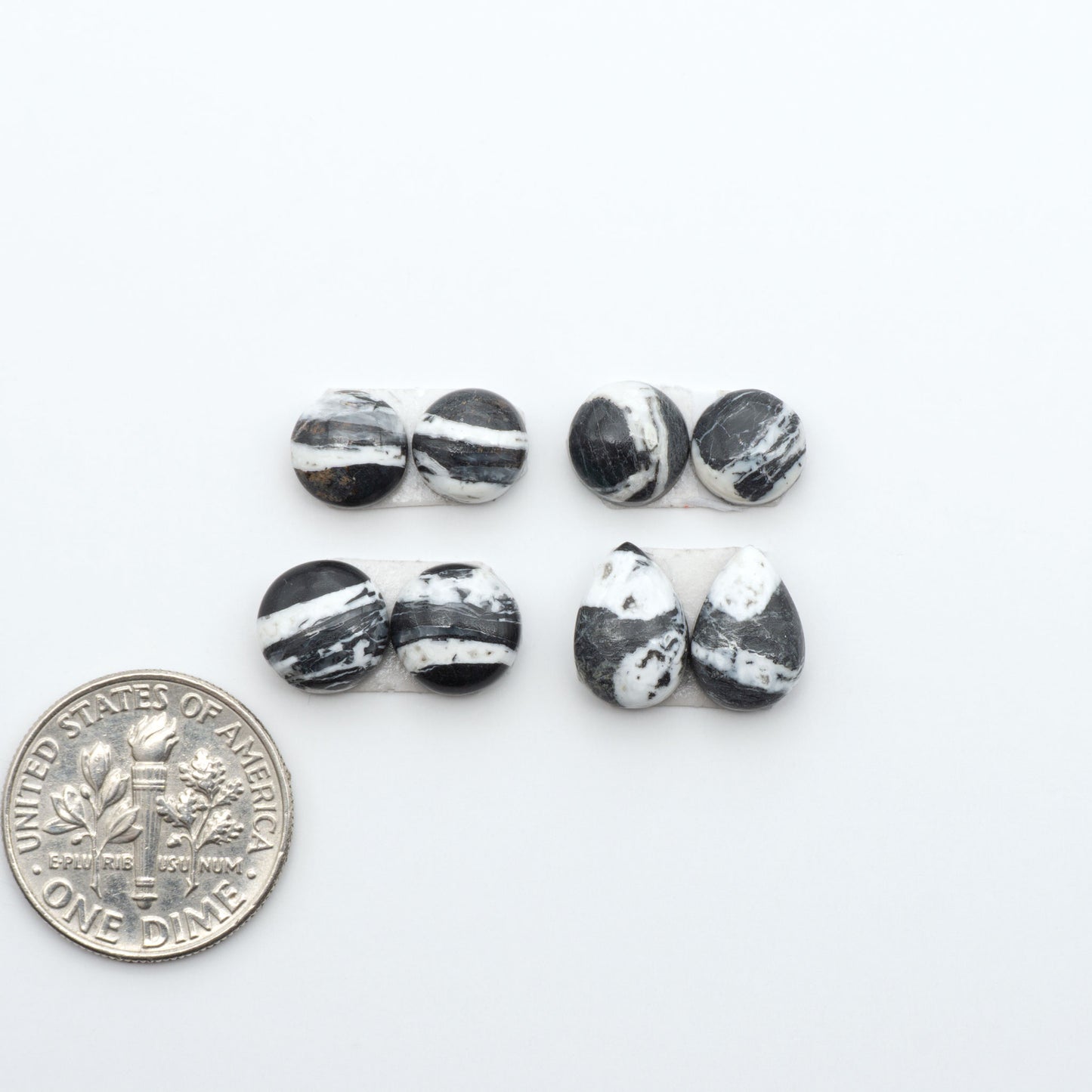 White Buffalo stone cabochons, white stone with black matrix, polished stones on a white background, with a US dime for scale