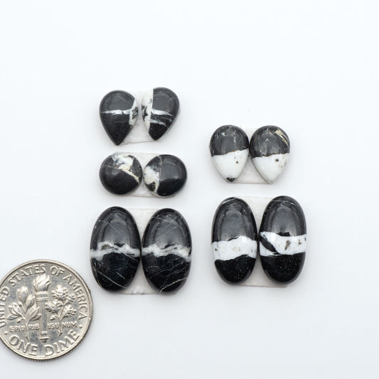 White Buffalo stone cabochons, white stone with black matrix, polished stones on a white background, with a US dime for scale